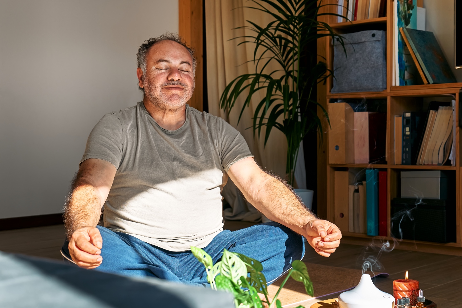 man practicing yoga and meditation at home sitting in lotus pose on yoga mat