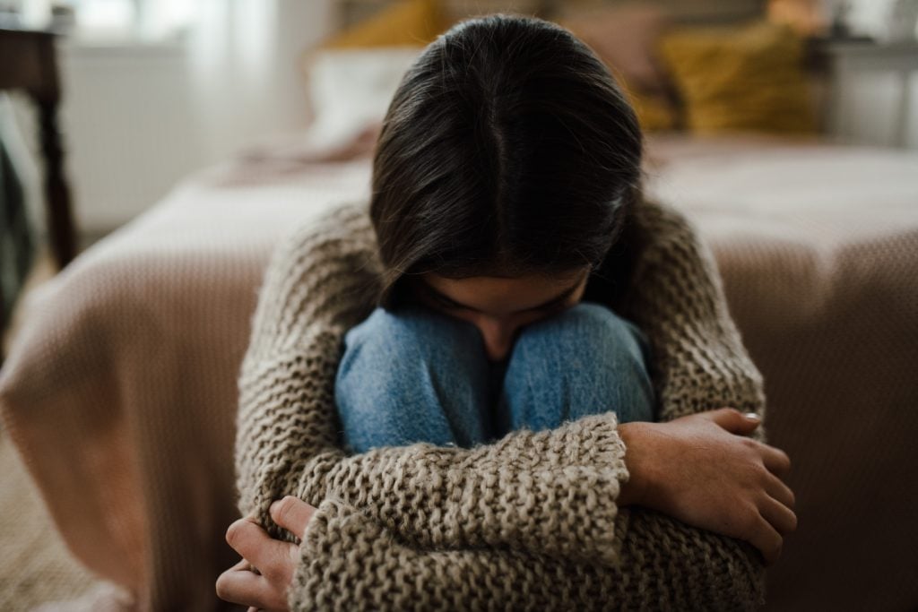 Girl sitting on the floor with head on knees, koncept of mental health.