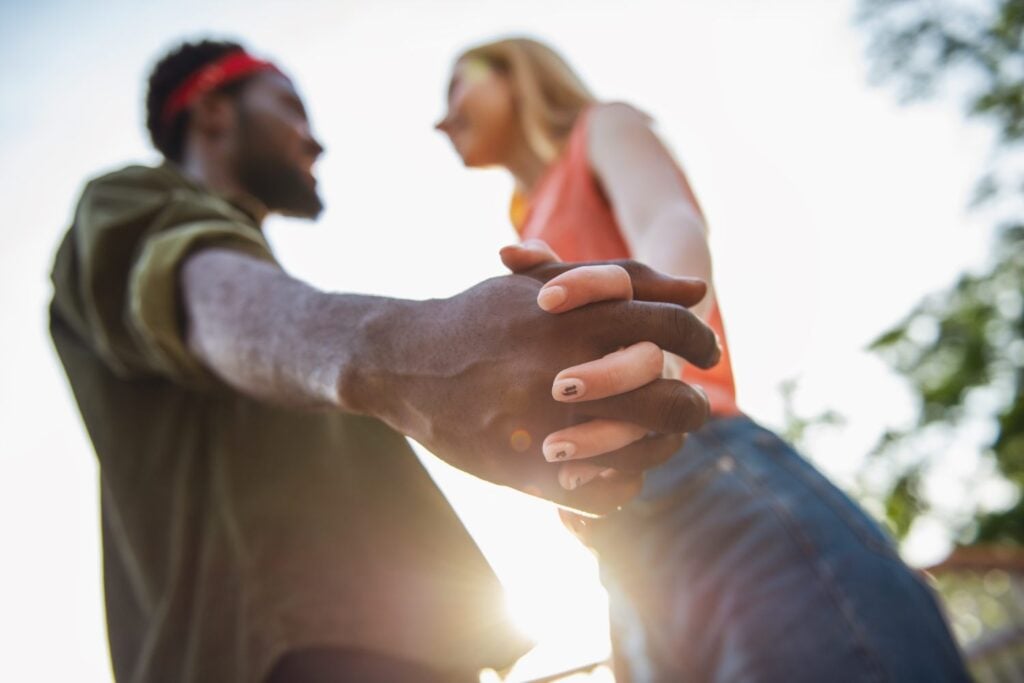 young couple standing while holding hands, focus on intertwined hands, concept of codependency