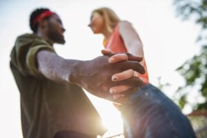 young couple standing while holding hands, focus on intertwined hands, concept of codependency