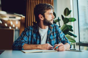 Pensive man writing in planner, concept of self awareness, mental health