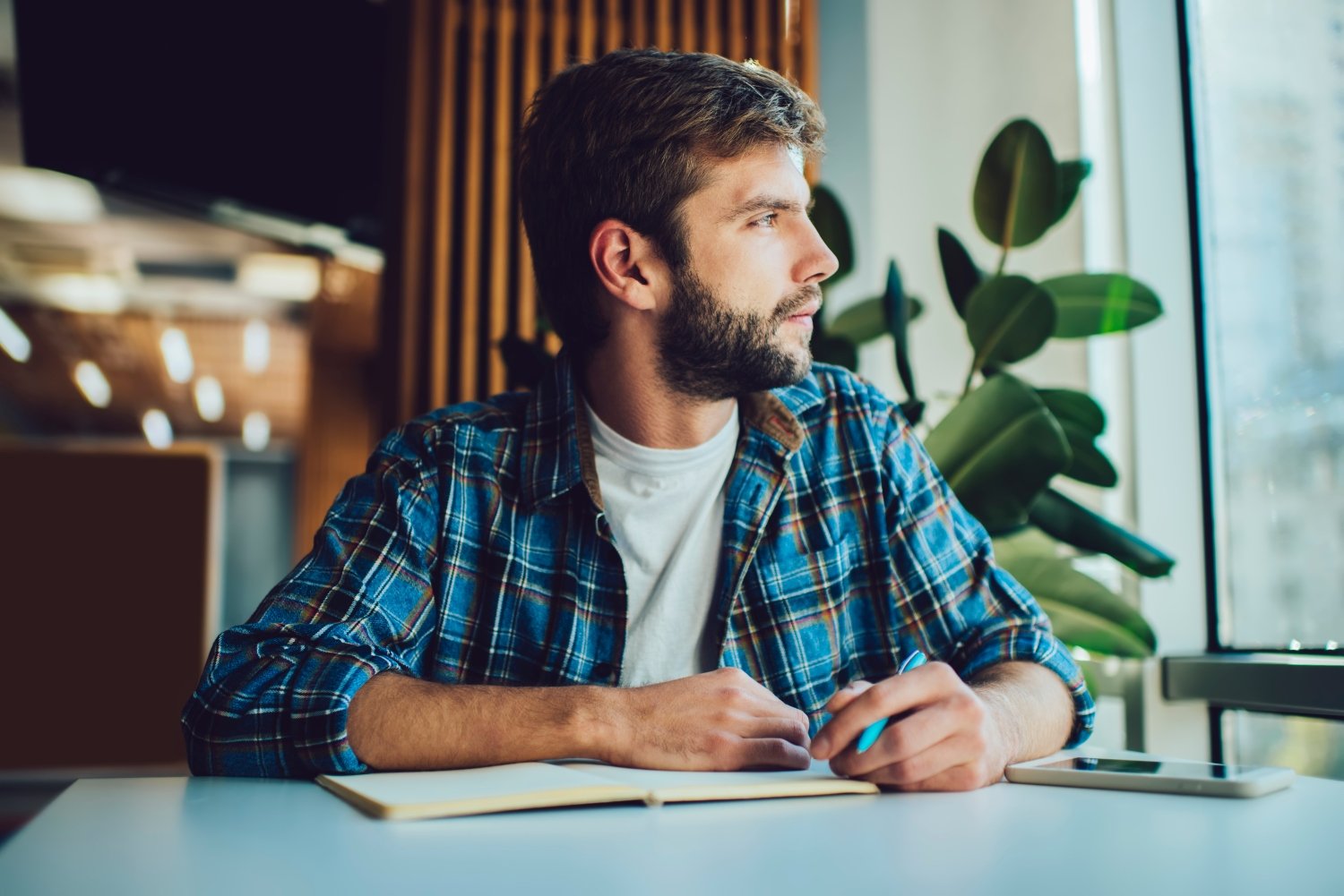 Pensive man writing in planner, concept of self awareness, mental health