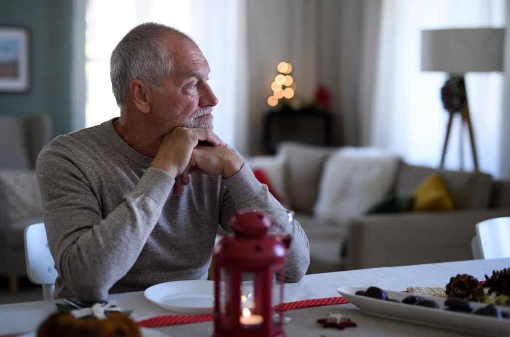 senior man sitting at the table indoors at Christmas