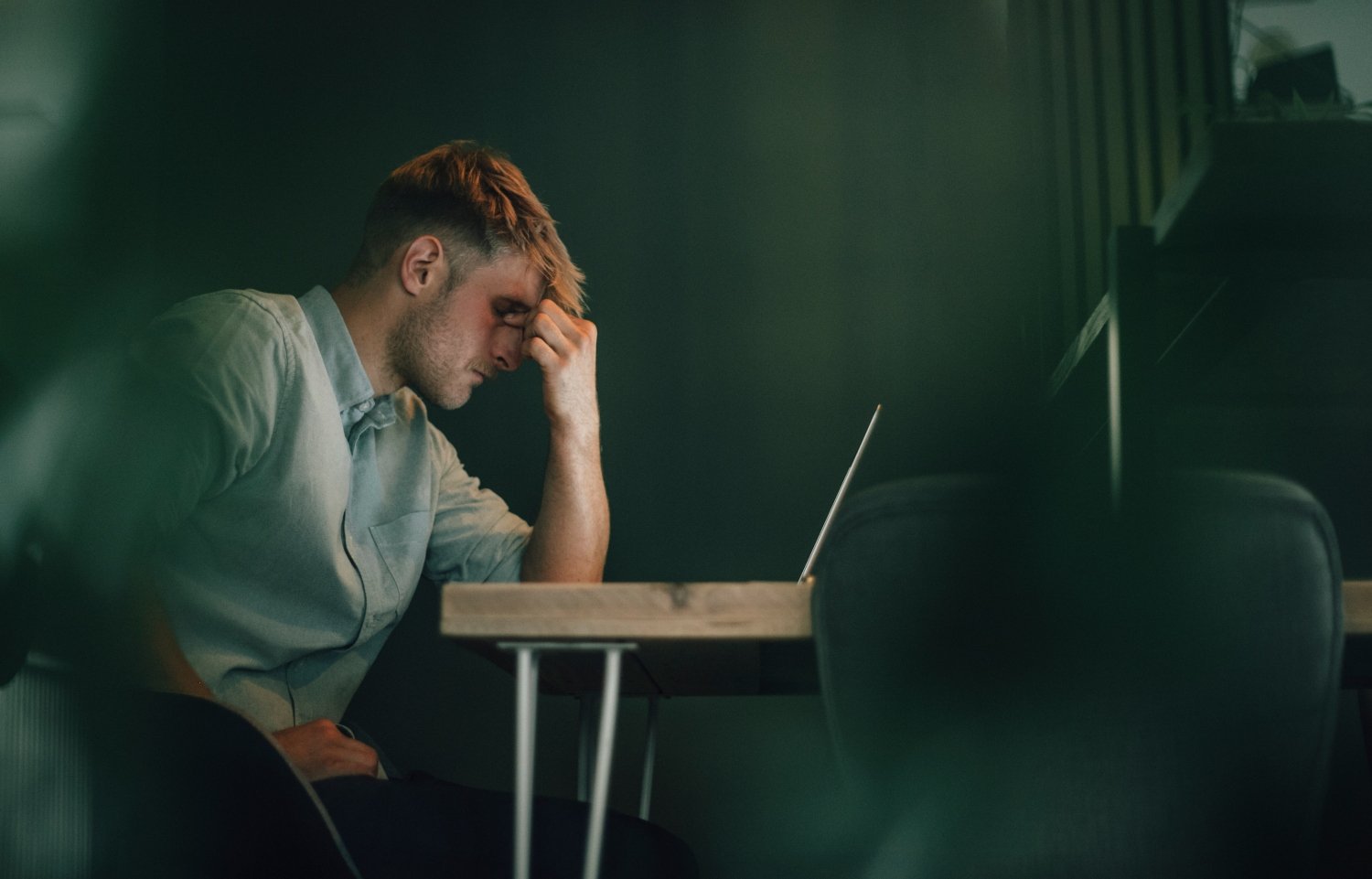 Tired man sitting in office, working late, concept of depression, burnout