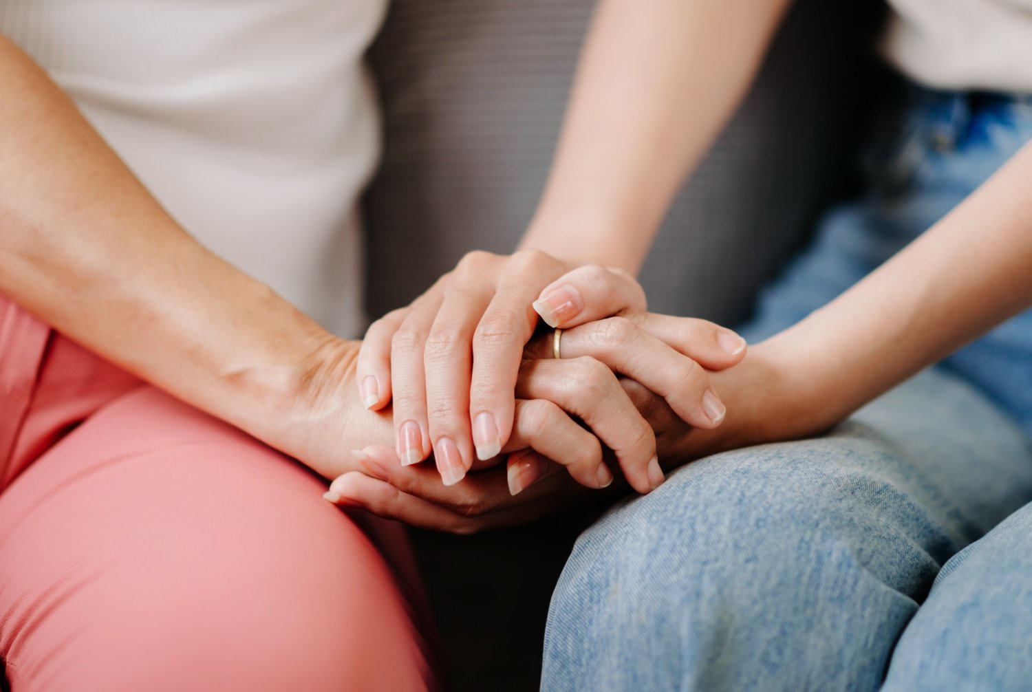 focused shot of mother's and adult daughter's hands, holding each other, concept of family support