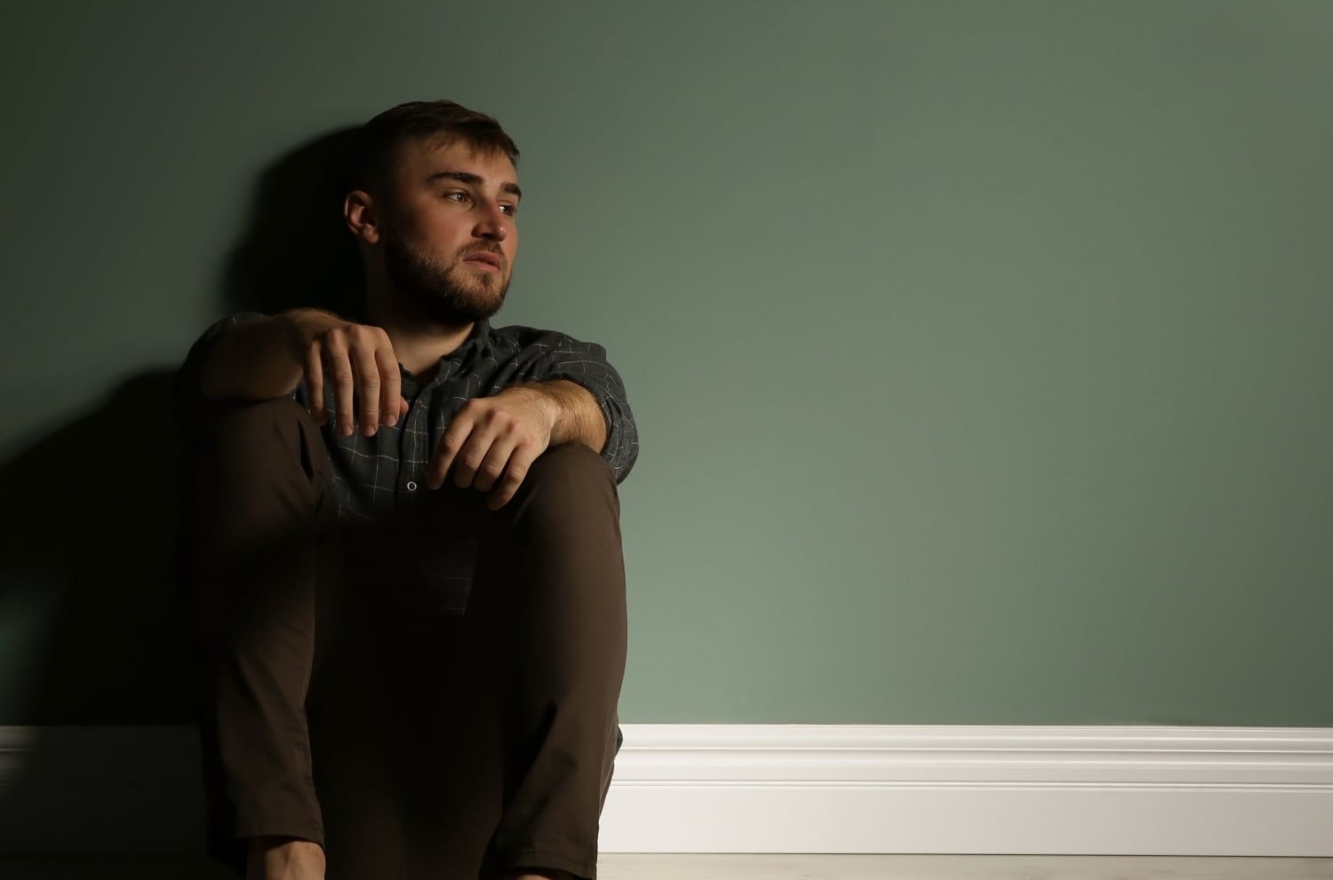 young man sitting on floor in darkness