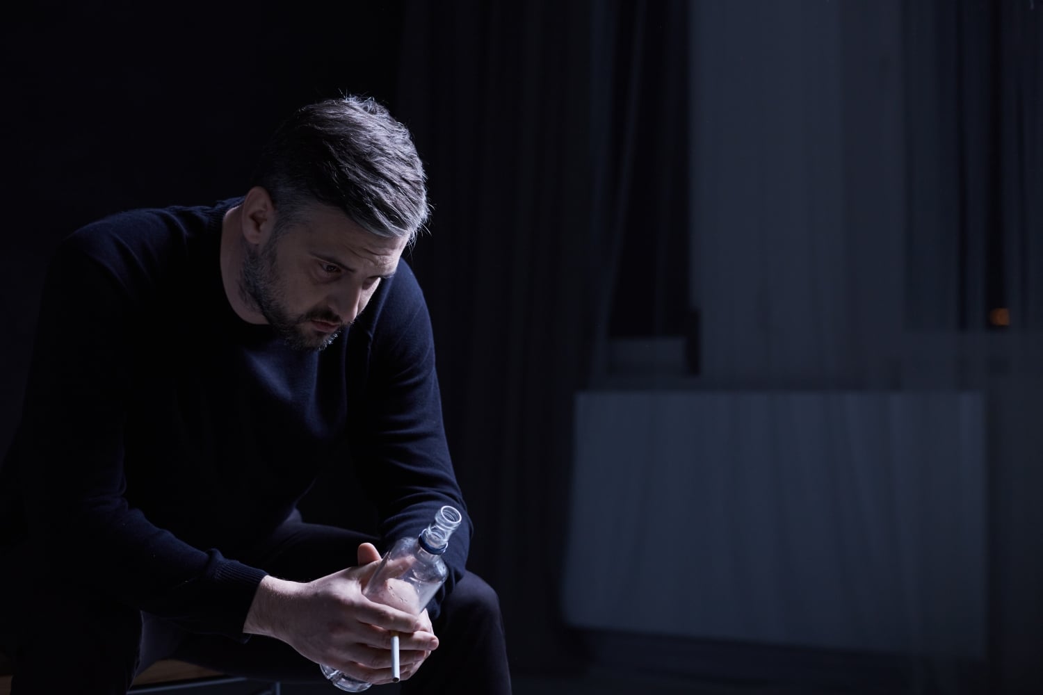 man holding a bottle of alcohol looking distressed