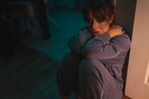 woman looking distressed while sitting on the floor in a dark room