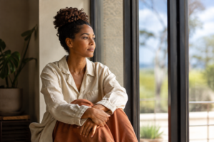 Woman seated by a window looking outside during a quiet, reflective moment